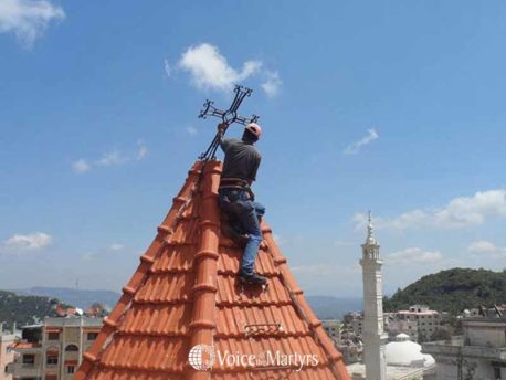 Syria man fixing cross on church